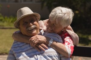 Front view of happy senior woman embracing senior man in garden